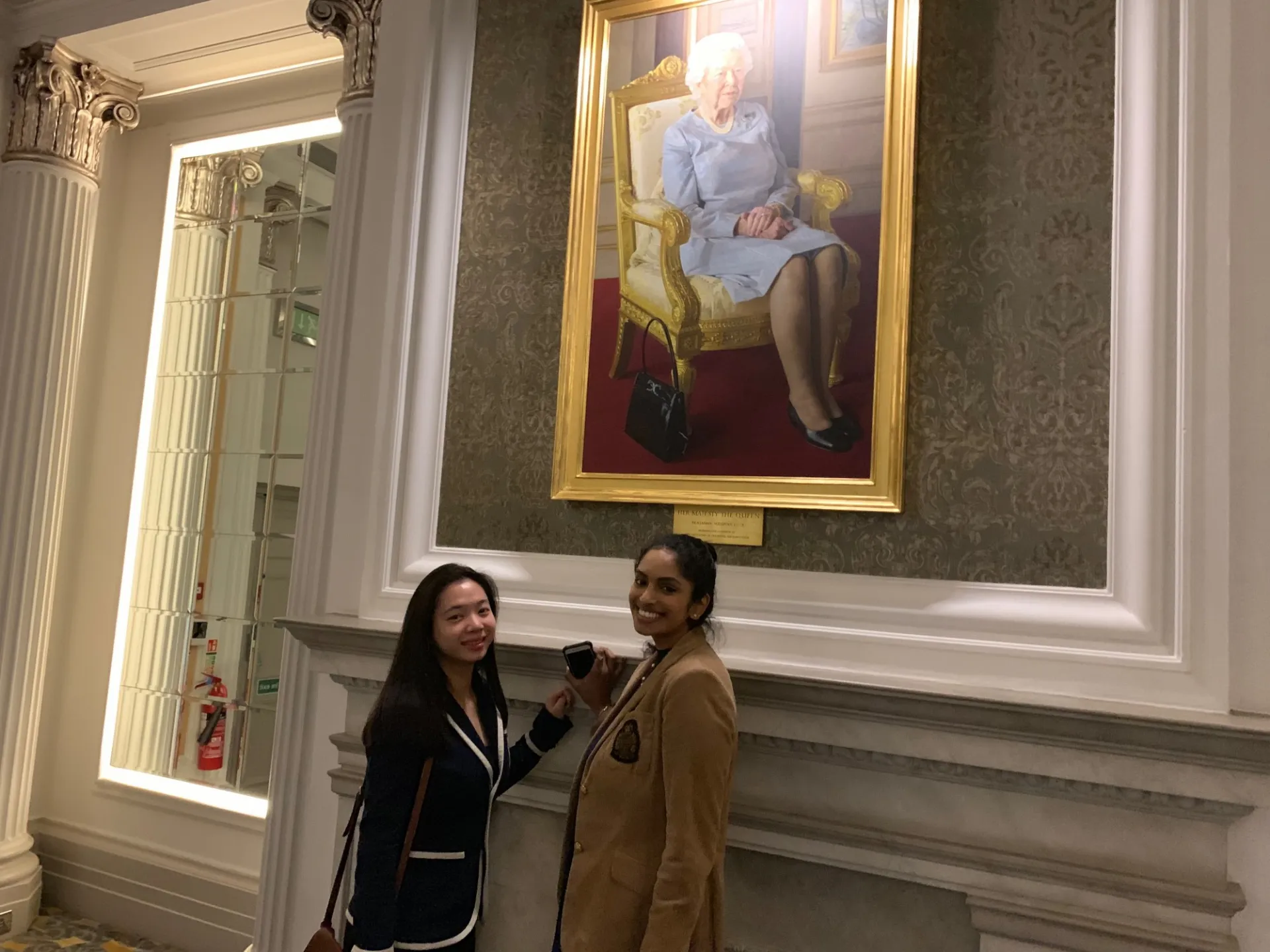 CWAR Fellows pose in front of a painting of Queen Elizabeth II at the Royal Air Force Club